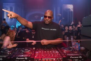 South African minimal dance music DJ performing in a dark club, showcasing subtle rhythm and deep electronic grooves